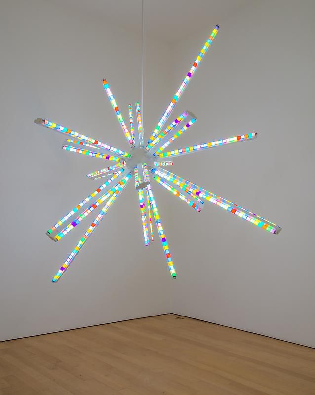 a white room with a multicolored light fixture hanging from it's ceiling