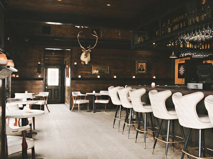 an empty bar with white chairs and deer heads on the wall