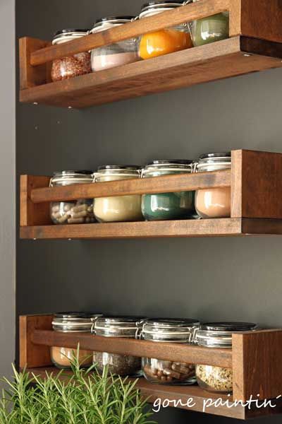 three wooden shelves with jars and spices on them