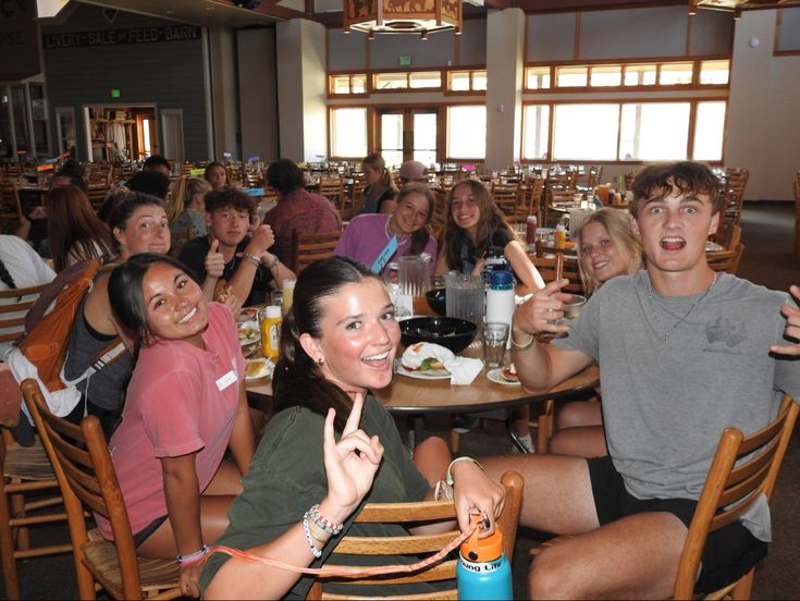 a group of people sitting around a table with food and drinks in front of them