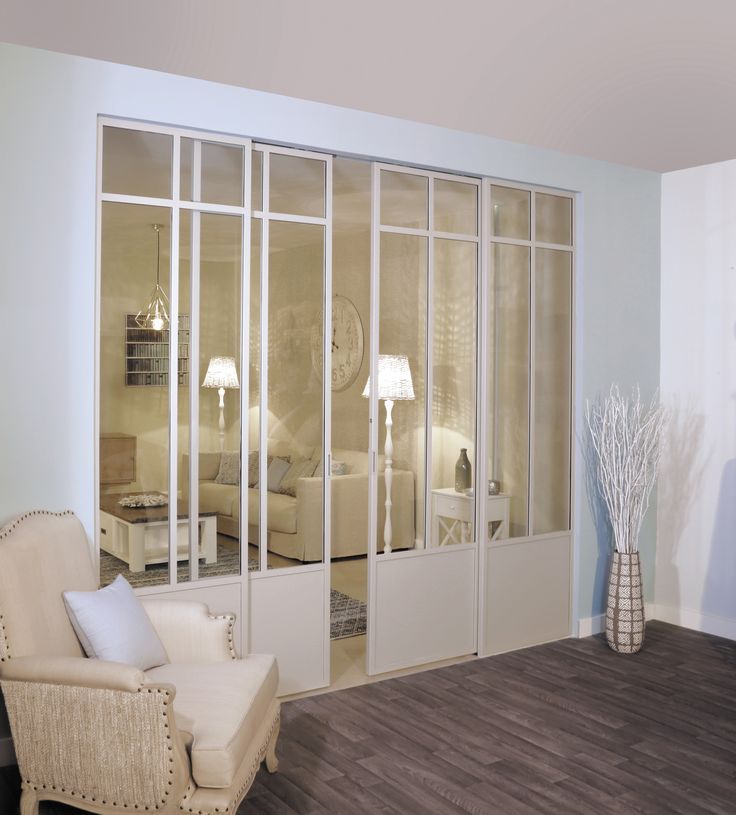 a living room filled with white furniture and lots of glass doors that open up to the outside