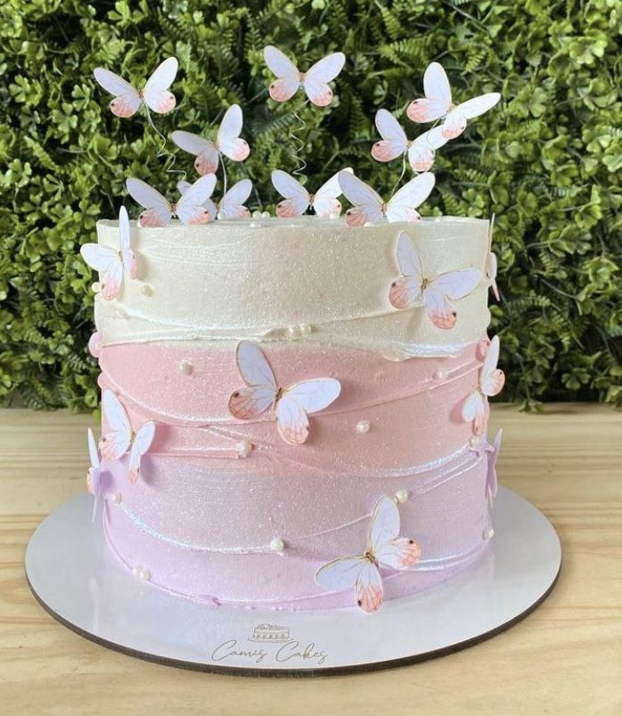 a pink and white cake with butterflies on top