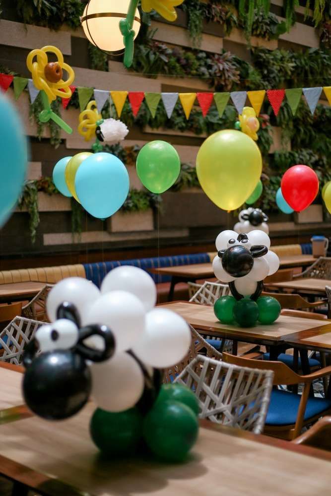 balloons are floating in the air near tables and chairs at a party with pandas on them