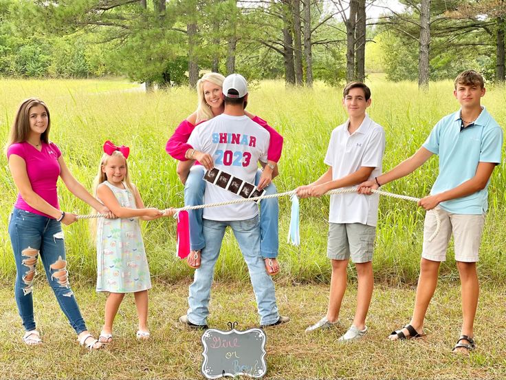 a group of people standing in the middle of a field holding onto a white rope