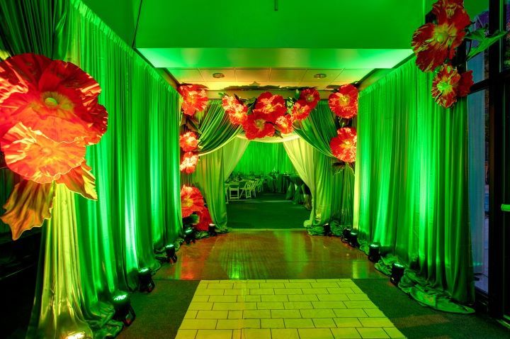 a long hallway decorated with red flowers and green drapes