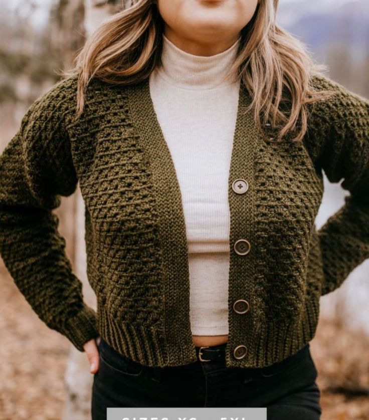 a woman standing with her hands on her hips wearing a green cardigan sweater and black jeans