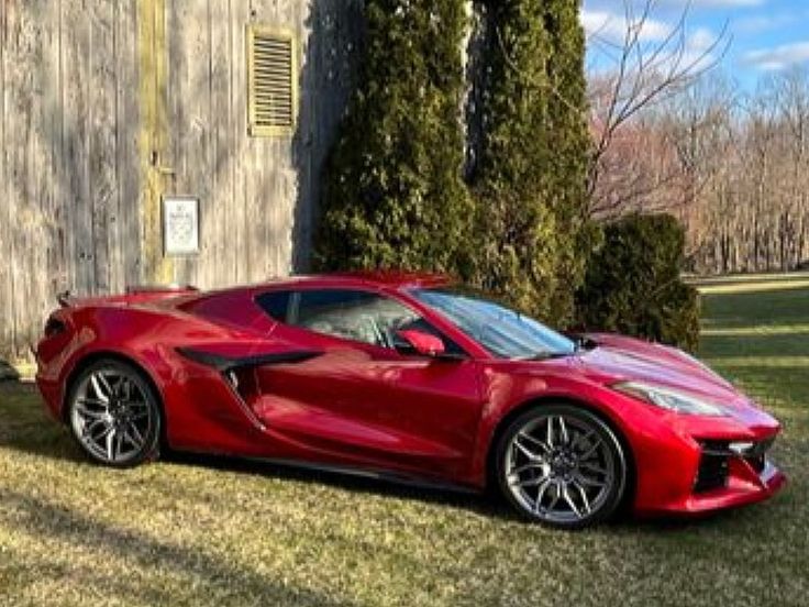 a red sports car parked in front of a barn