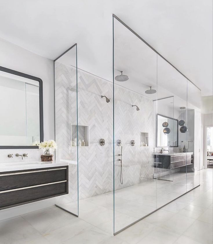 a large bathroom with glass walls and marble counter tops, along with a walk in shower