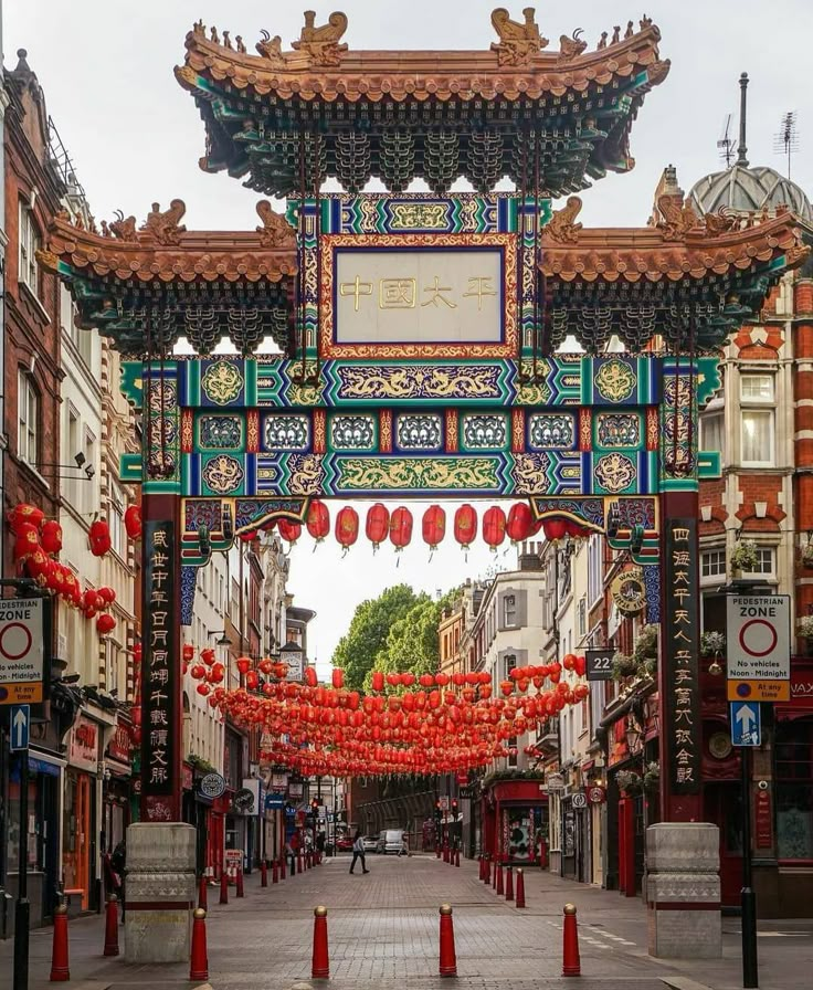 an archway in the middle of a street with red lanterns hanging from it's sides