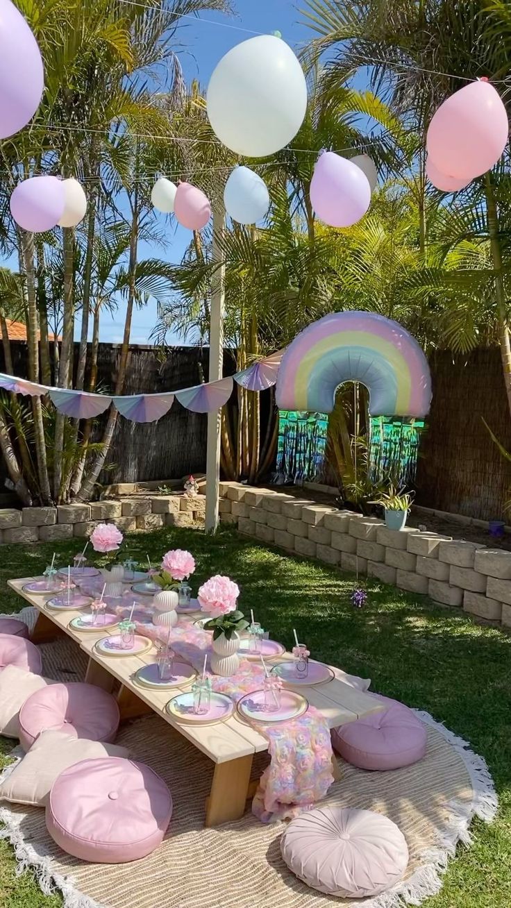 a picnic table set up with pink and white balloons