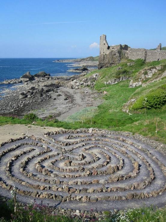 a stone maze in the middle of a field next to an ocean