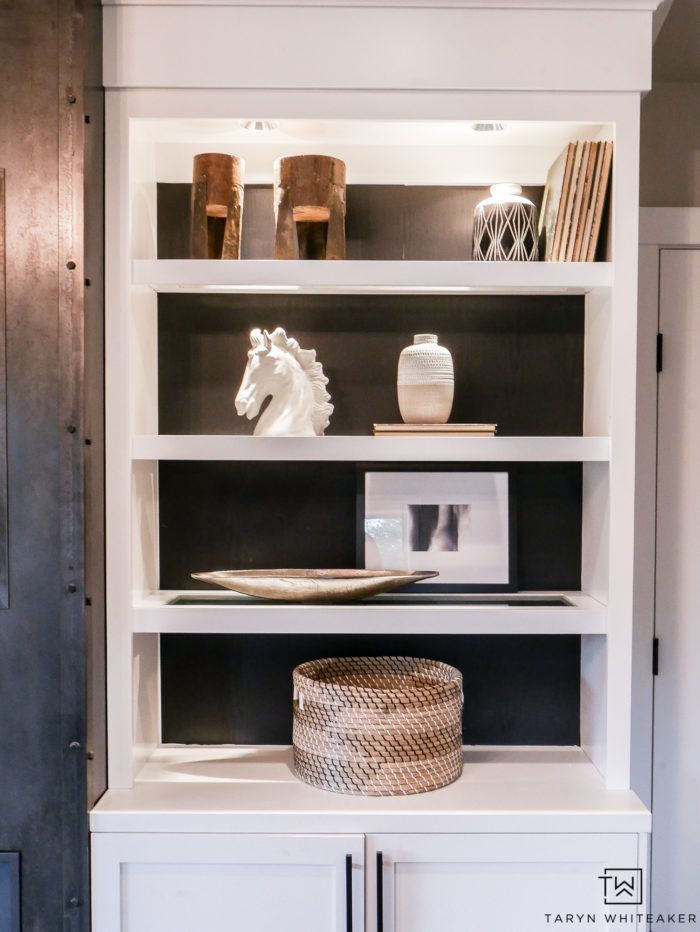 a white bookcase with books and vases on top