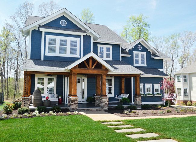 a blue house with white trim and two story windows on the second floor is surrounded by green grass