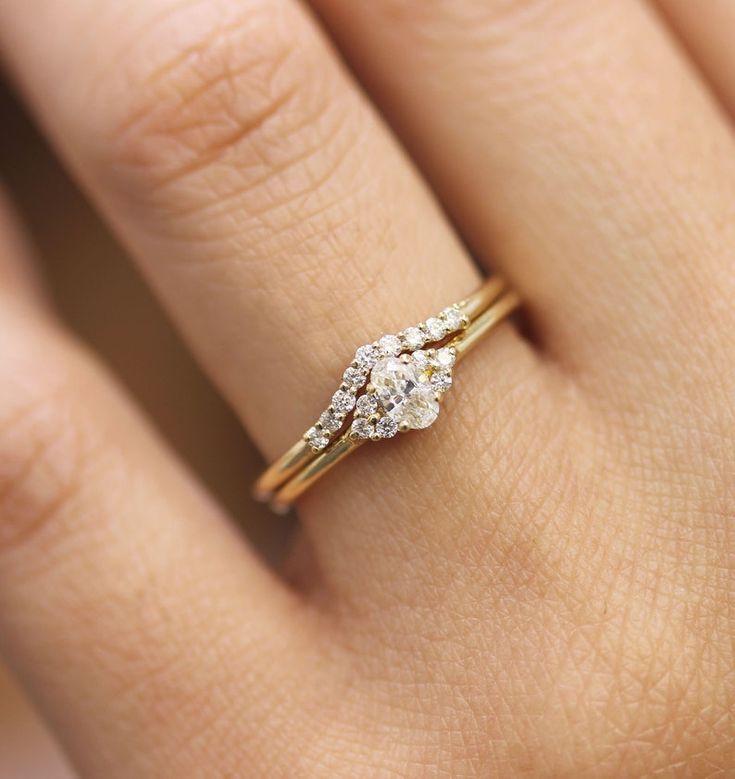 a woman's hand with a diamond ring on top of her finger and an engagement band