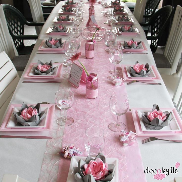 a long table is set with pink and gray place mats, napkins, and wine glasses