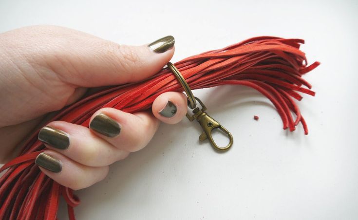 a hand holding a pair of scissors with red tassels