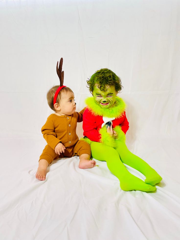 two babies dressed up in costumes sitting next to each other on a white background,