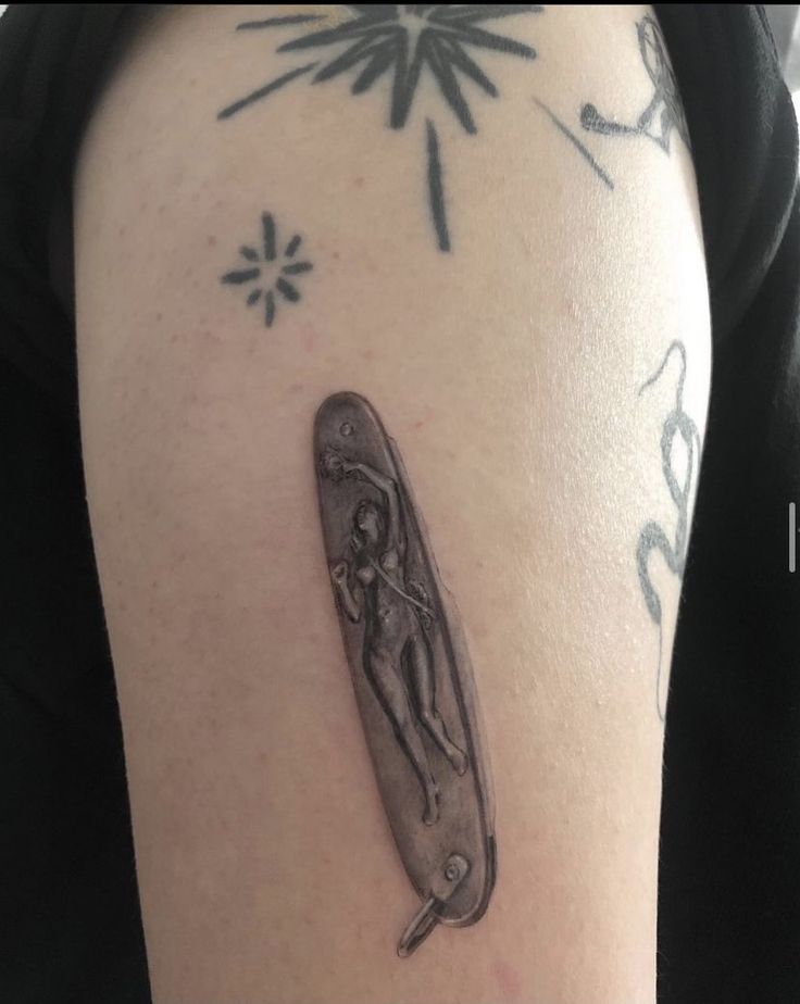 a person with a tattoo on their arm holding an object in the shape of a knife