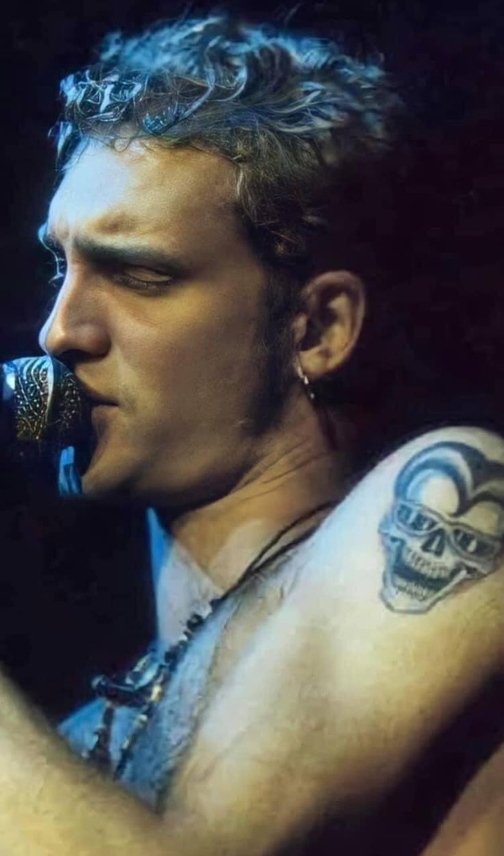 a man with tattoos on his arm singing into a microphone