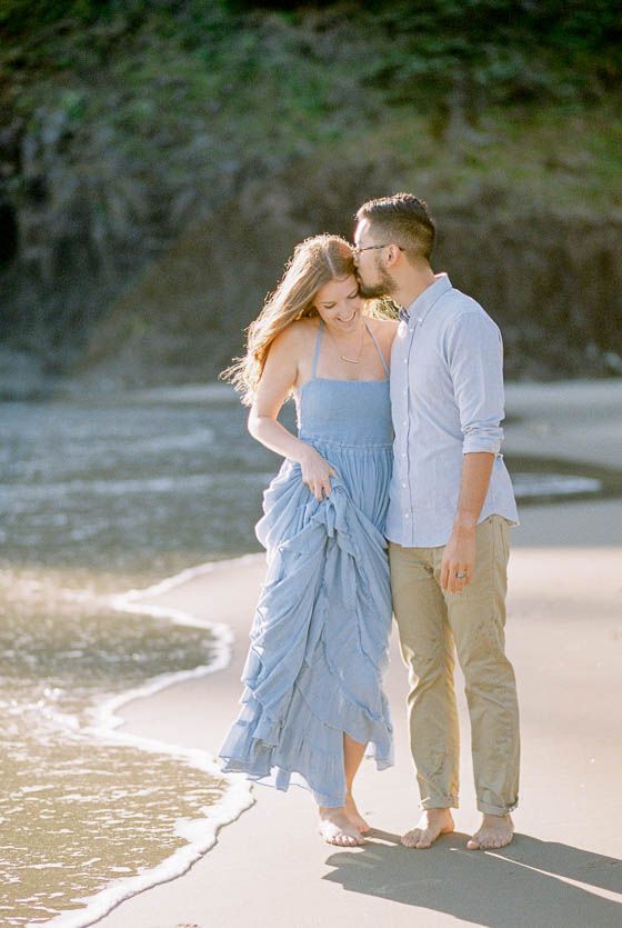 a man and woman are standing on the beach