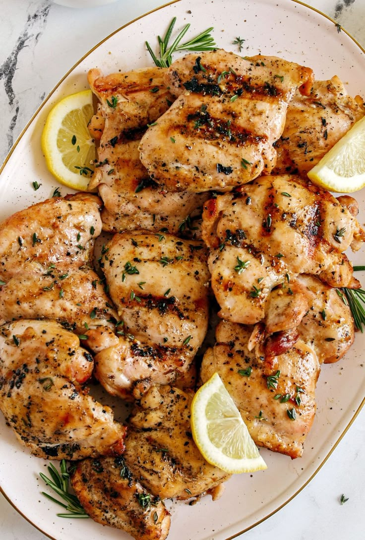 grilled chicken with lemons and herbs on a white plate, ready to be eaten