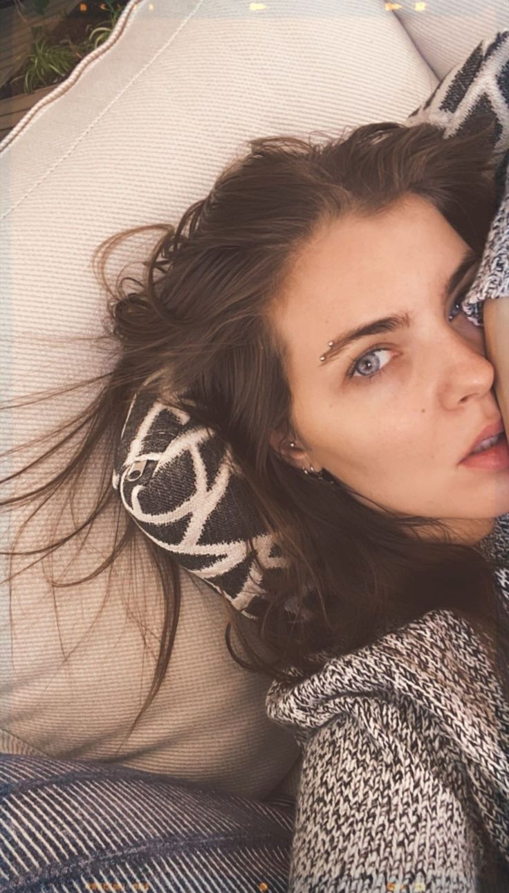 a woman laying on top of a white pillow