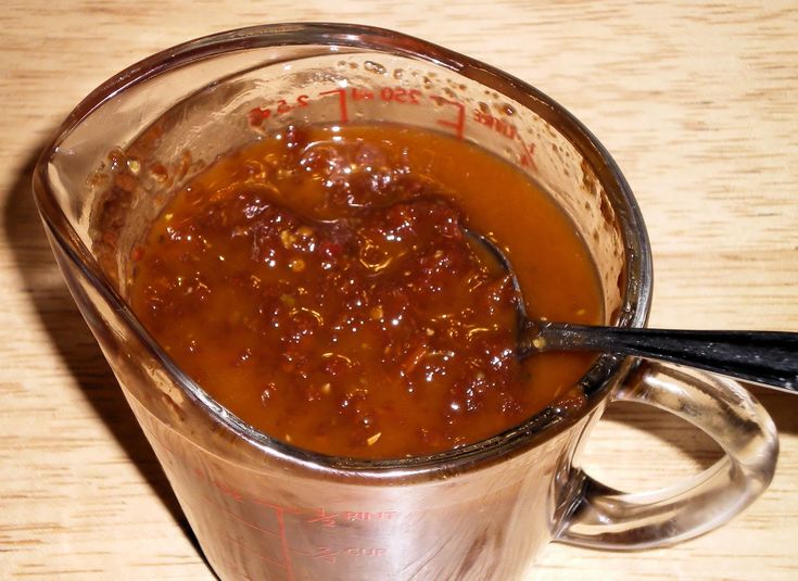 a glass measuring cup filled with sauce on top of a wooden table