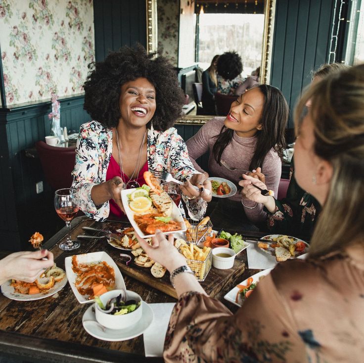 three women sitting at a table with plates of food