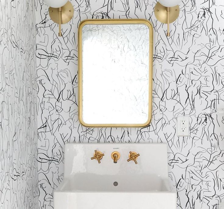 a white sink sitting under a mirror next to a gold faucet in a bathroom