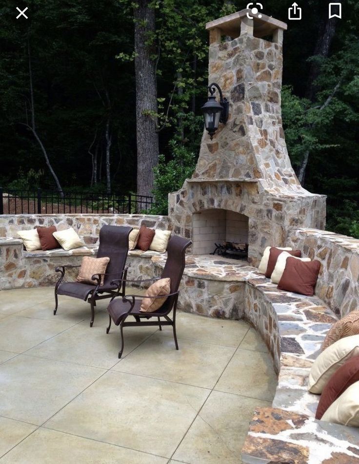 an outdoor patio with stone fireplace and seating