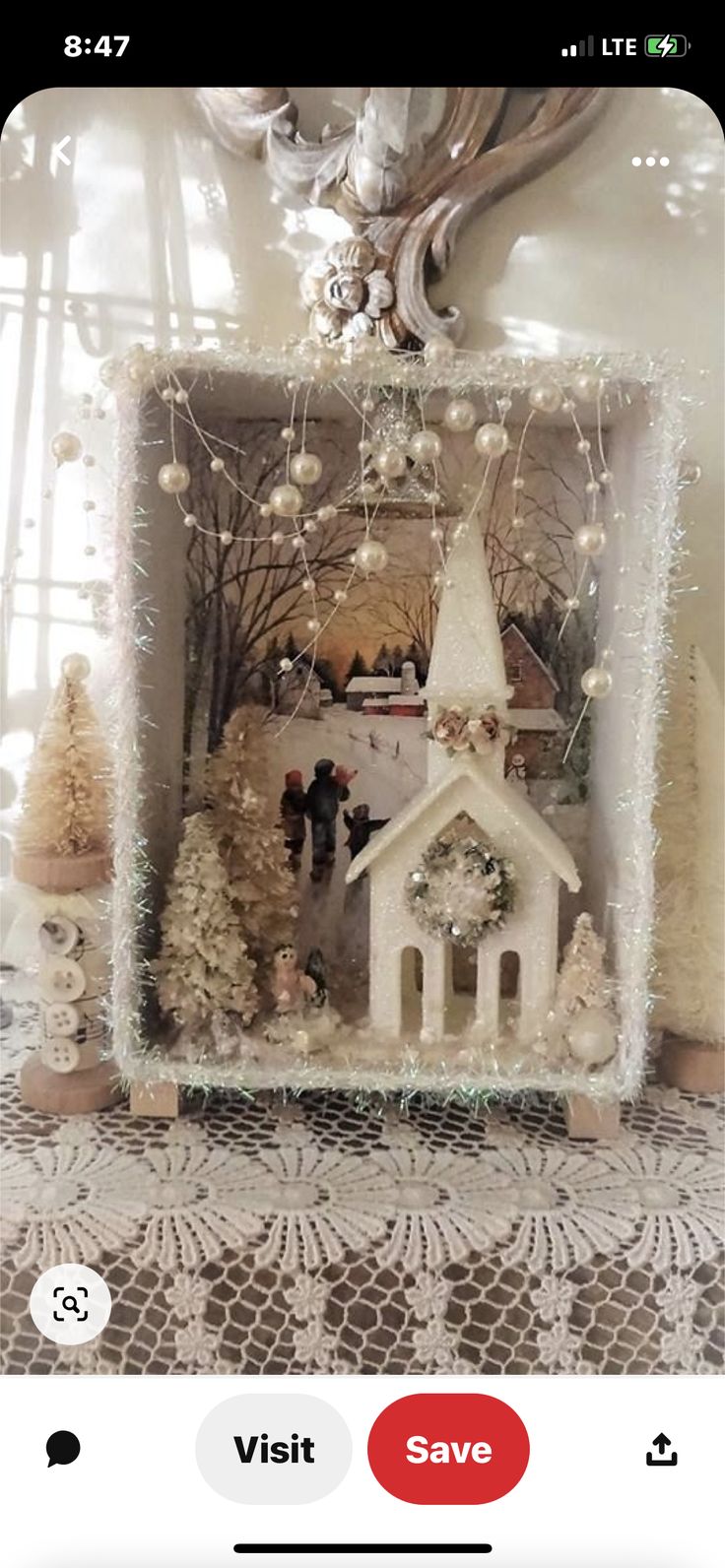 a small white church surrounded by christmas trees and other holiday decorations in a window frame