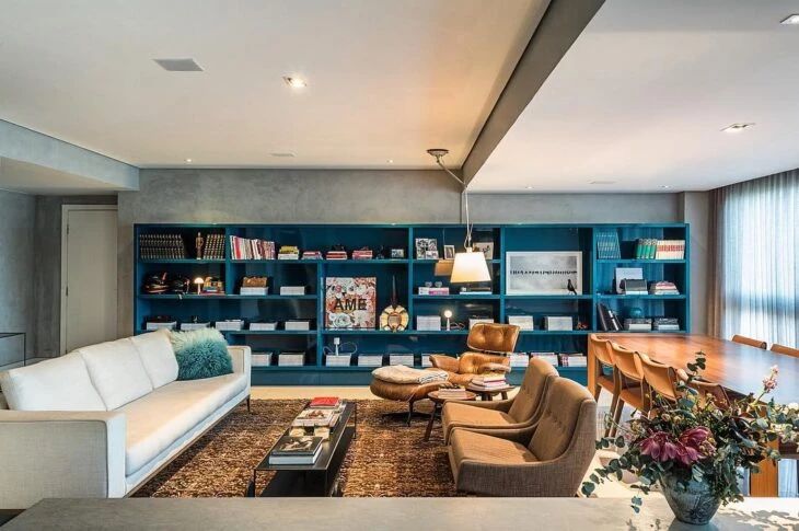 a living room filled with lots of furniture next to a wall covered in bookshelves