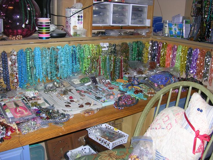 a room filled with lots of different colored beads and necklaces on display next to a chair