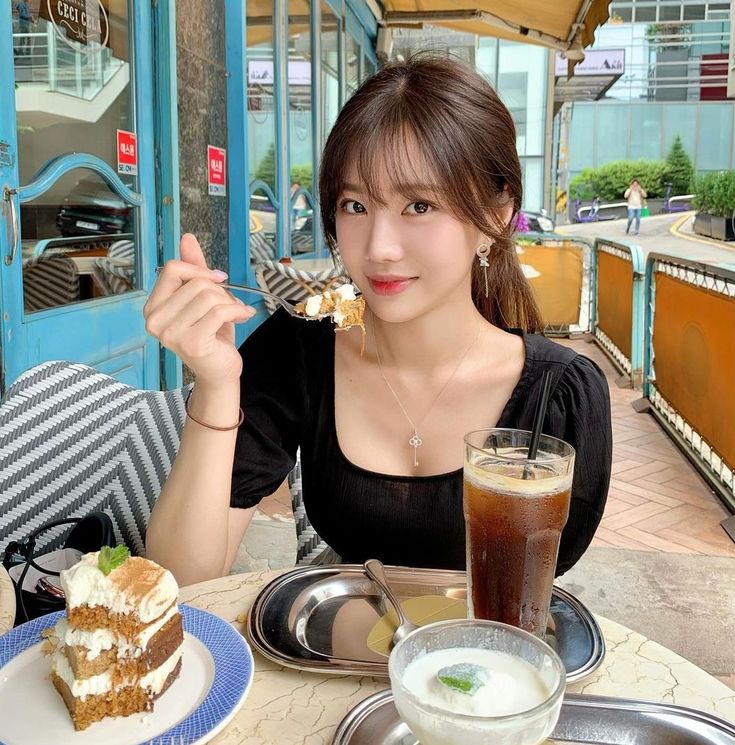 a woman sitting at a table with food in front of her and drinks on the side