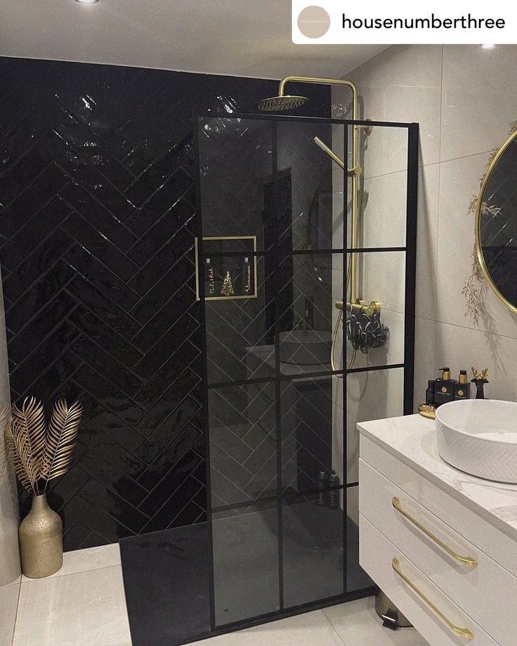 a black and white bathroom with gold accents on the shower, sink and toilet area