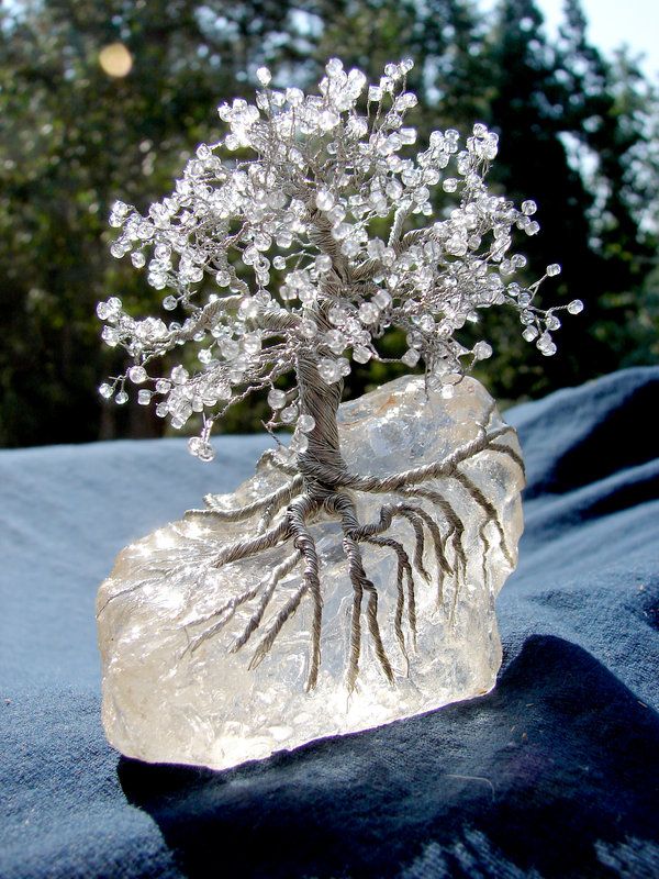 a crystal tree on top of a rock with roots growing out of it's base