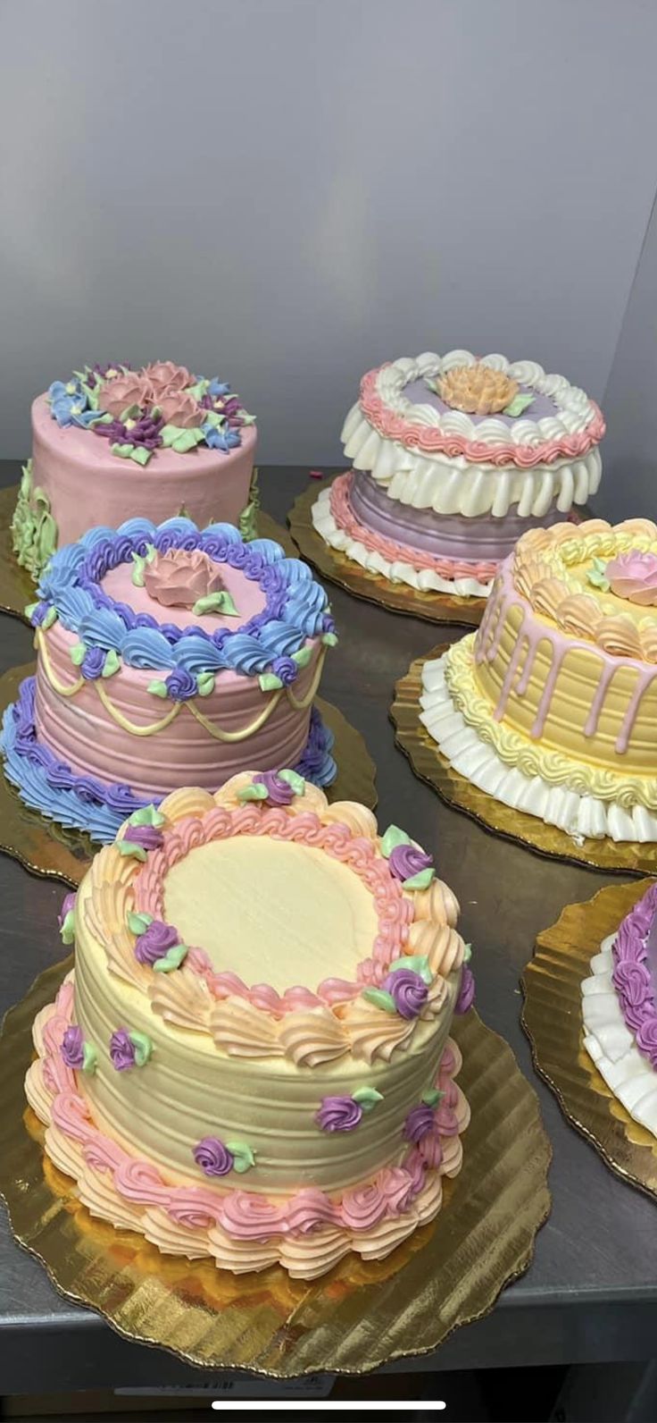 there are many different cakes on the table and one is pink, blue, yellow and white