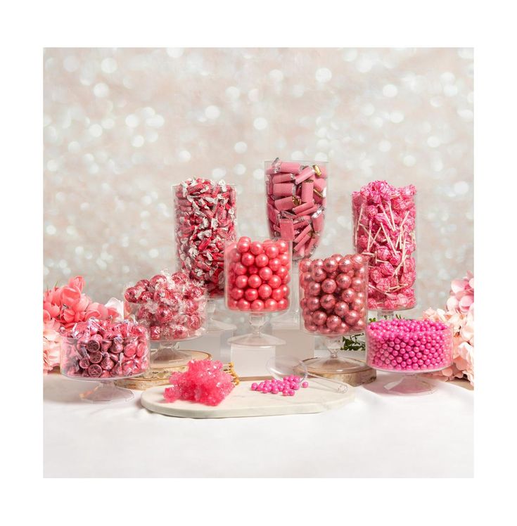 there are many pink and white candies in the glass vases on the table