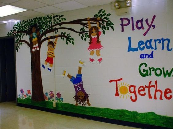 a classroom wall painted with children's pictures and words that read play learn and grow together