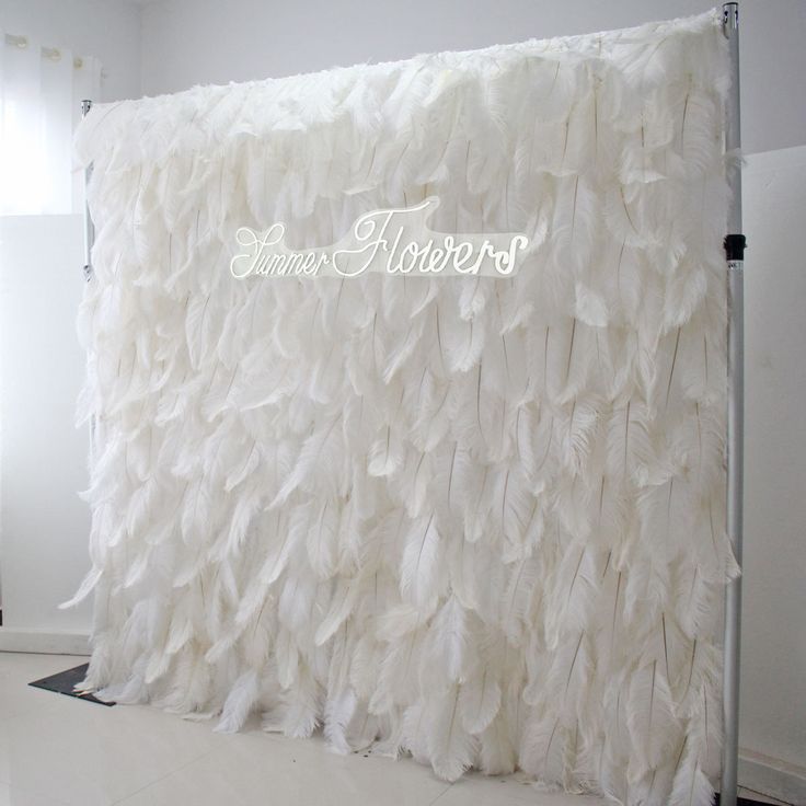 a room with a large white curtain made out of feathers on the wall next to a window