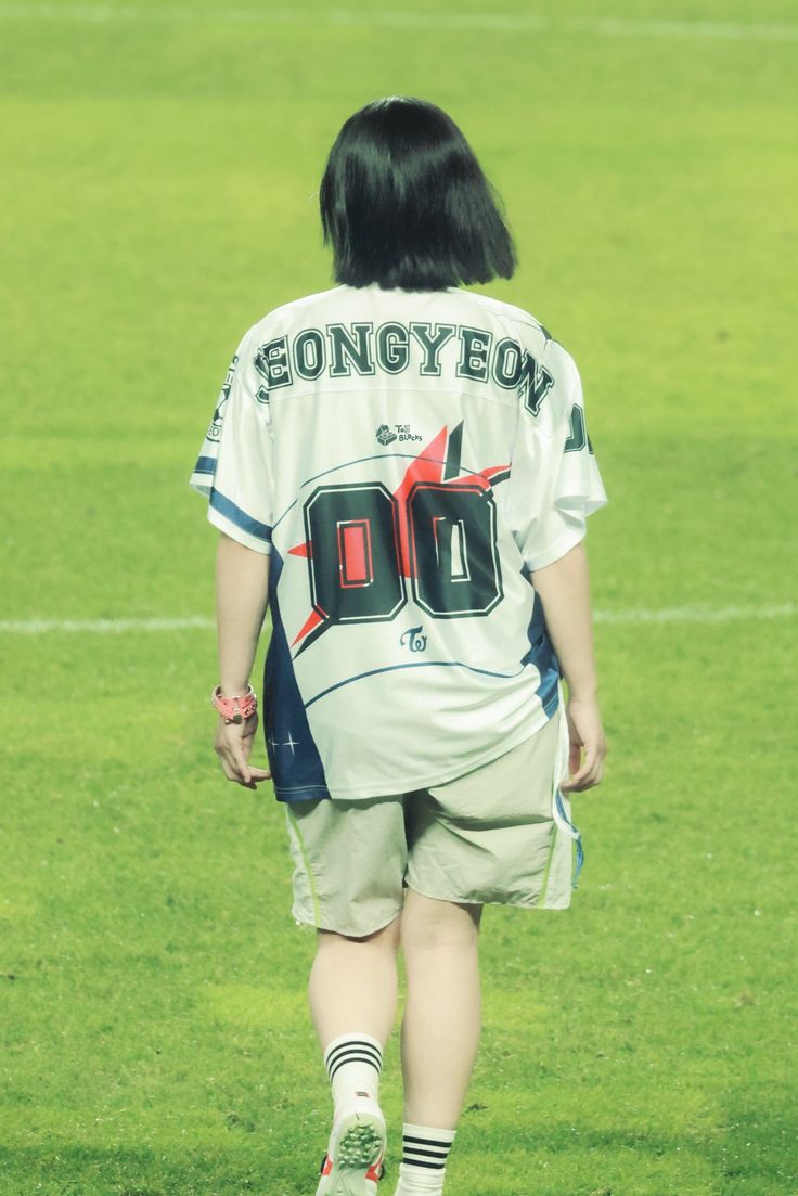 a woman walking across a soccer field wearing a jersey with the number 00 on it