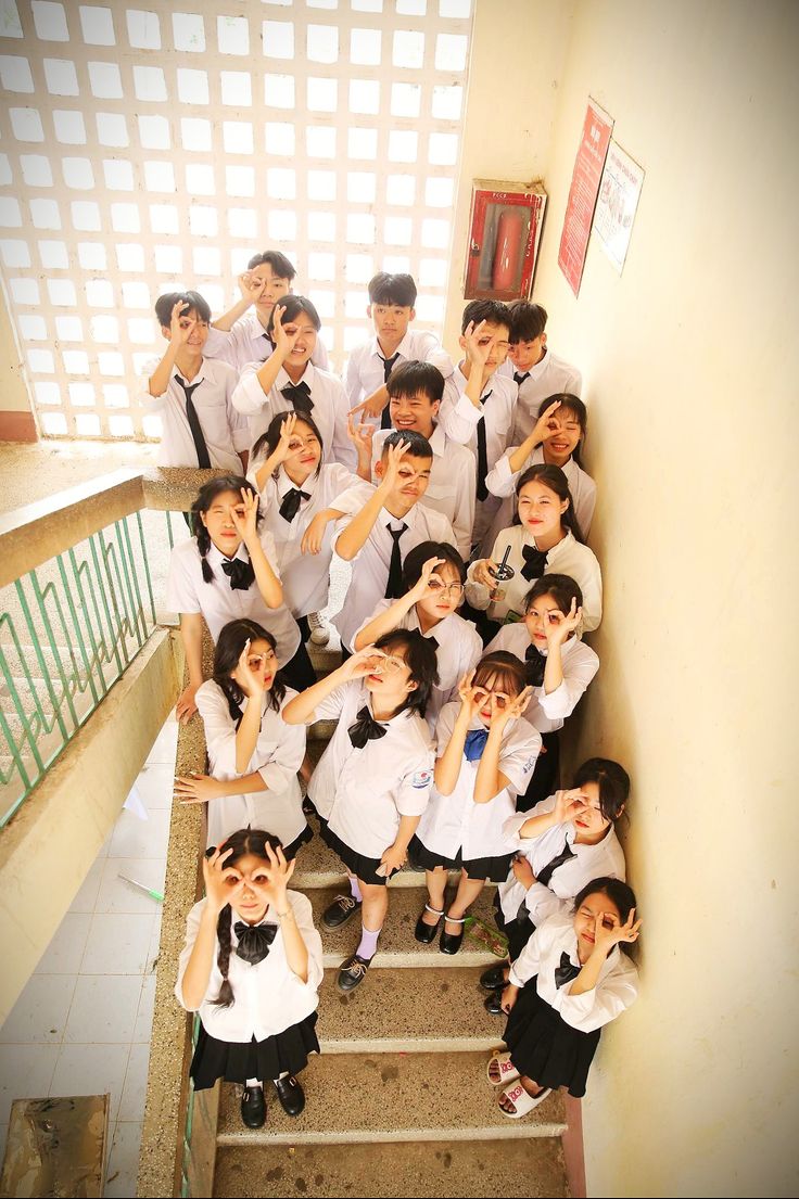 a group of young people posing for a photo on the stairs with their hands up in the air