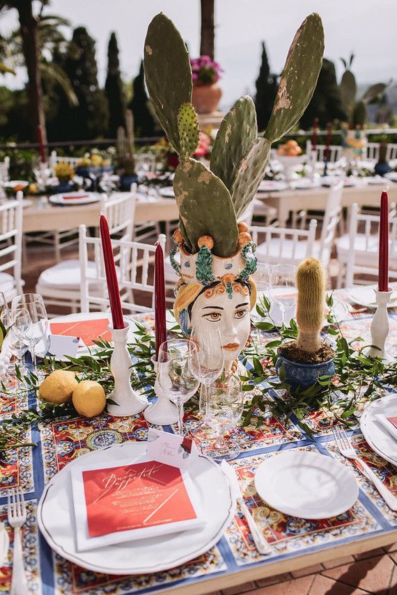 a table is set with plates, silverware and cactus head decorations for a mexican themed wedding