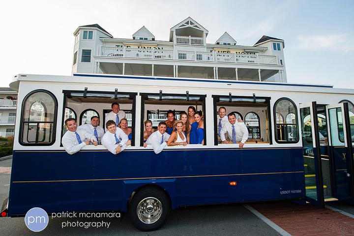 a group of people standing on the side of a blue and white bus in front of a building