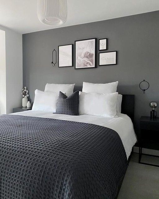 a bedroom with gray walls and white bedding, pictures on the wall above the bed