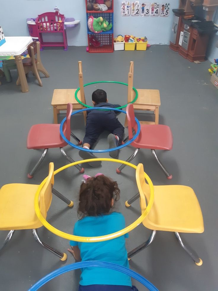 two children playing with toys in a play room at the same time as they sit on their own chairs