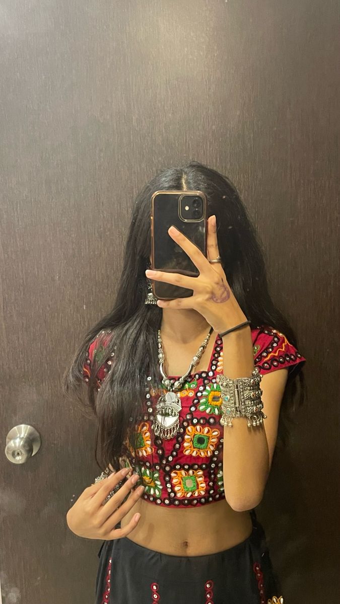 a woman taking a selfie in front of a mirror with her cell phone up to her face