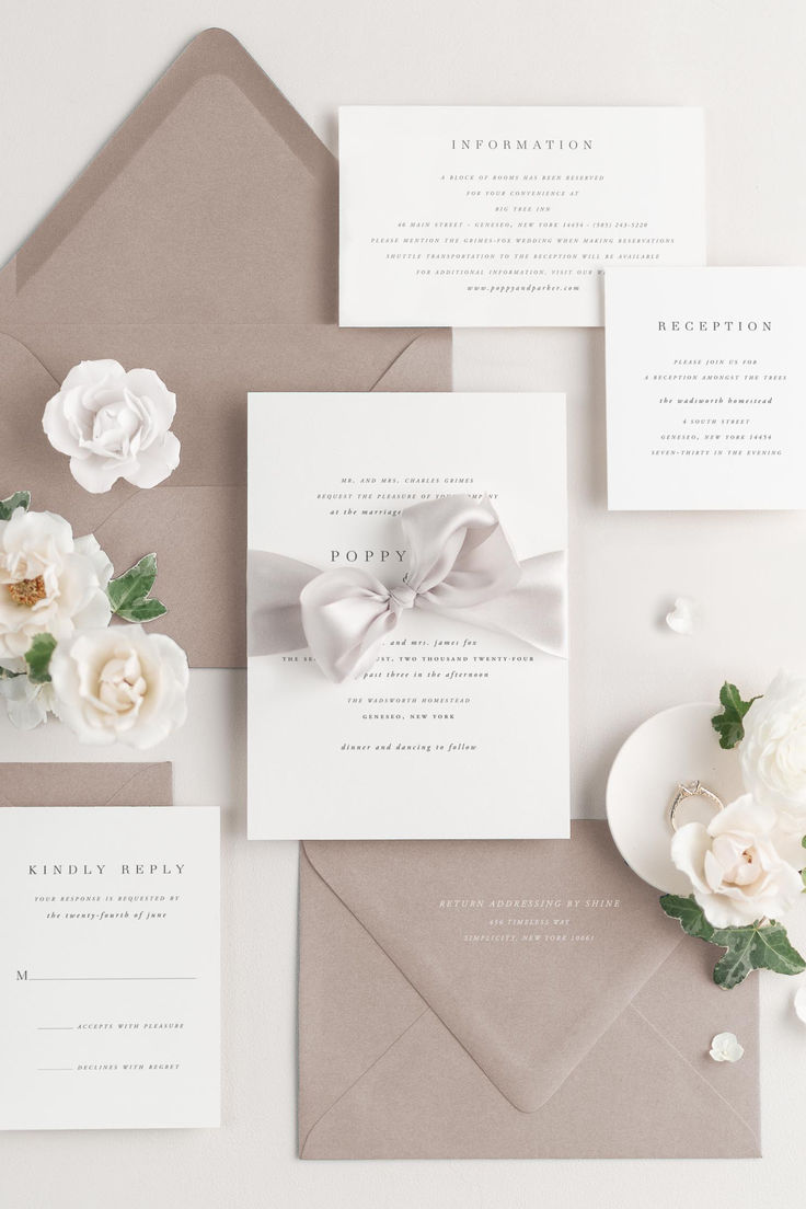 the wedding stationery is laid out on top of an envelope, with white flowers and greenery