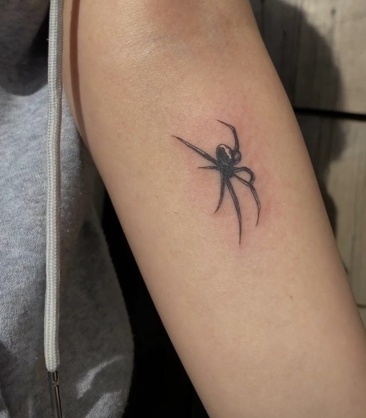 a small black spider tattoo on the arm