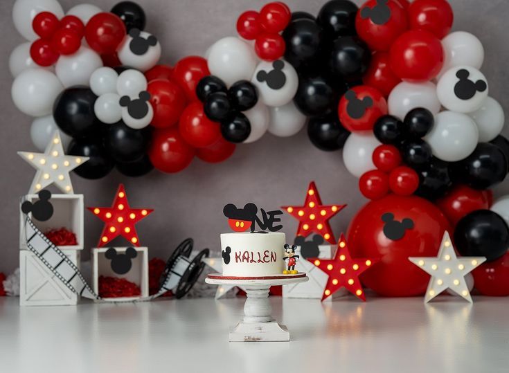 a mickey mouse themed birthday party with balloons and decorations on the table, including a cake